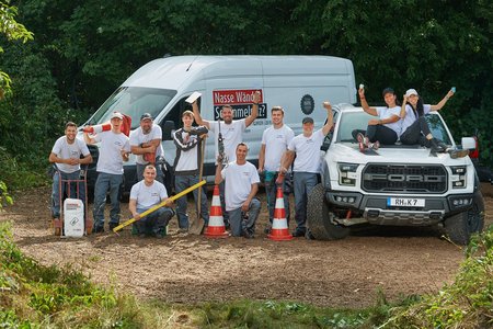 ISOTEC Team posiert mit Werkzeugen vor Transporter und Pickup